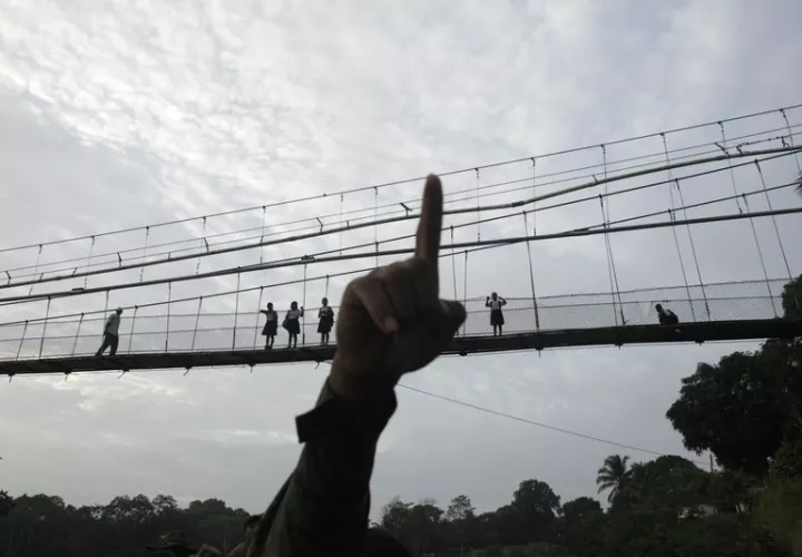 En esta foto del 19 de junio de 2018, un policía de fronteras señala mientras empieza a patrullar en la provincia del Darién, frontera con Colombia, en Yaviza, Panamá. (AP Foto/Arnulfo Franco, Archivo)