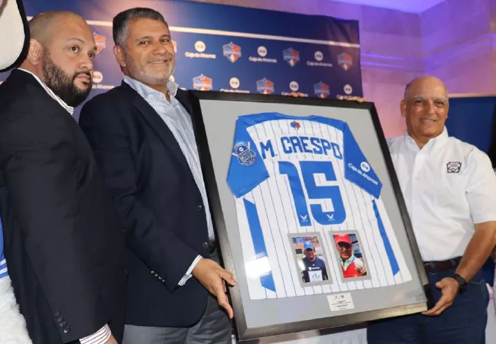 Martín Crespo (der.) recibe un obsequio en la conferencia en la que se oficializa la dedicatoria del Nacional de Béisbol Juvenil a su persona.