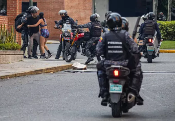 Guardia Nacional Bolivariana (GNB) detienen a dos personas durante protestas. Foto: EFE